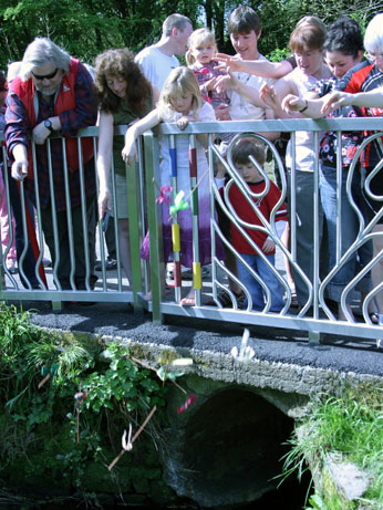 Image of people playing pooh sticks at launch of Bridge