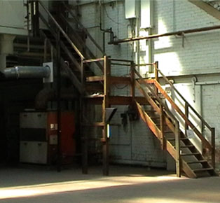 speaker hidden in large silver pipe next to steep wooden stairs above small stro light - Mary Sutton's installation